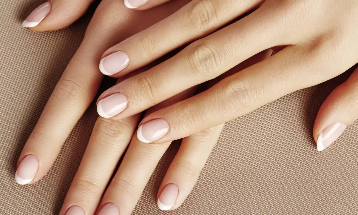Dłonie z klasycznym french manicure. Delikatny róż i biel tworzą subtelny french pomarańczowy, podkreślając elegancję.