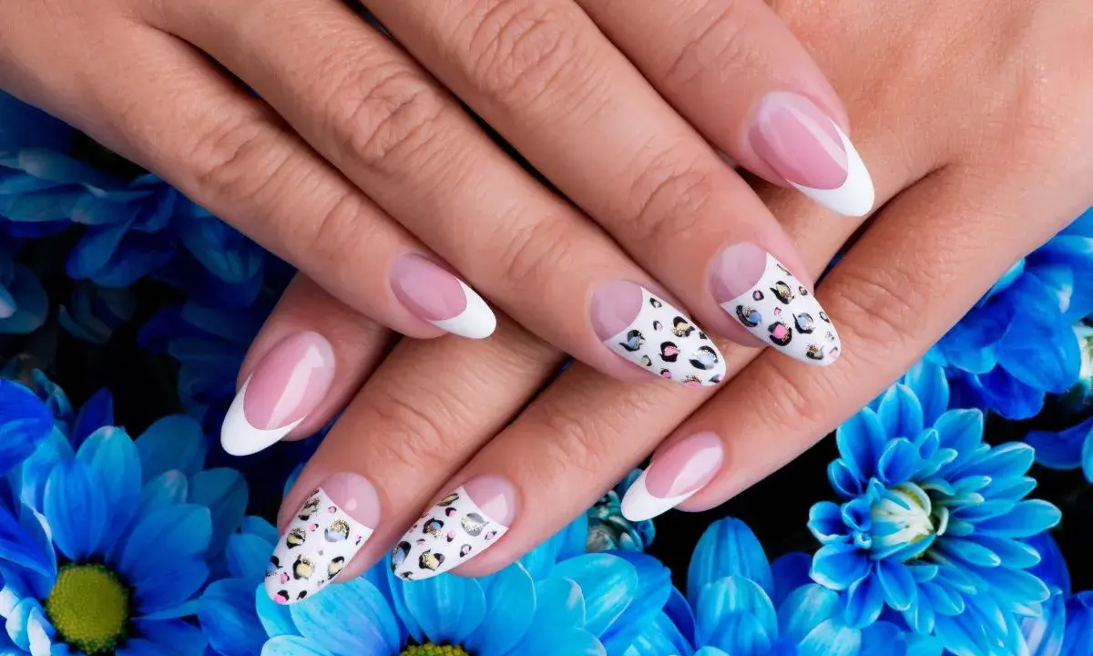 Dłonie z idealnym manicure, gdzie paznokcie na których nie widać odrostu zdobią klasyczny french i wzór panterki.
