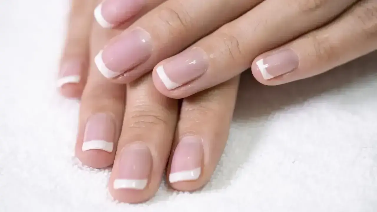 Dłonie z perfekcyjnym french kombinowanym manicure. Delikatny róż i biel podkreślają elegancję.