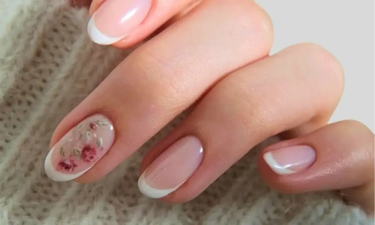 Delikatne paznokcie ślubne boho z subtelnym zdobieniem w postaci różowych kwiatów na jednym z paznokci. Klasyczny french manicure w nowoczesnym wydaniu.