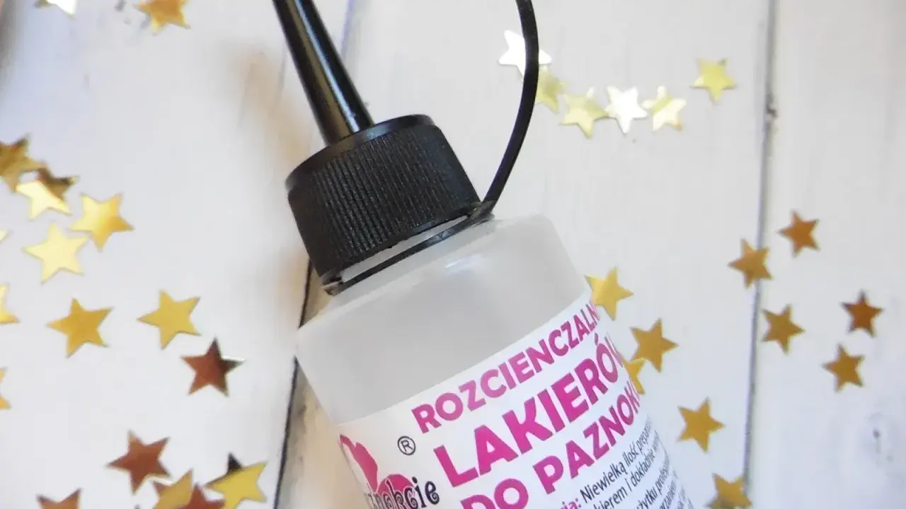 Butelka rozcieńczalnika do lakieru do paznokci, otoczona złotymi gwiazdkami.