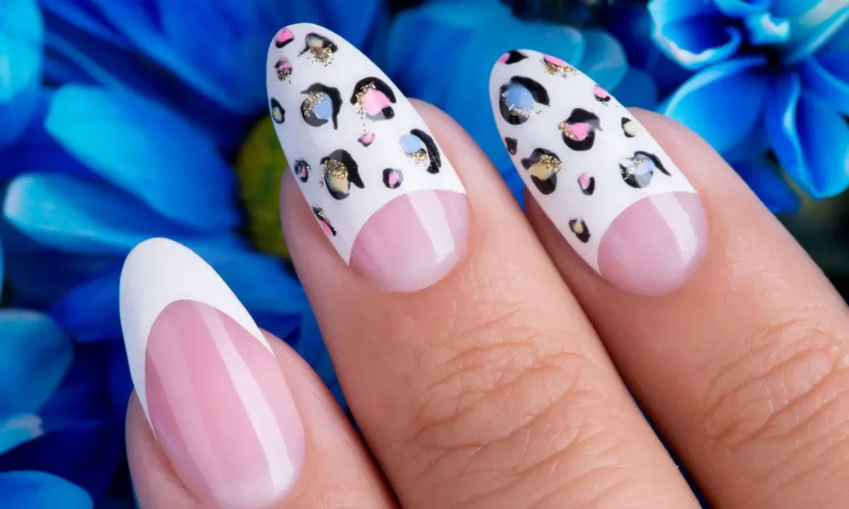 Dłonie z perfekcyjnym manicurem. Paznokcie na których nie widac odrostu, ozdobione wzorem panterki i klasycznym french manicure.
