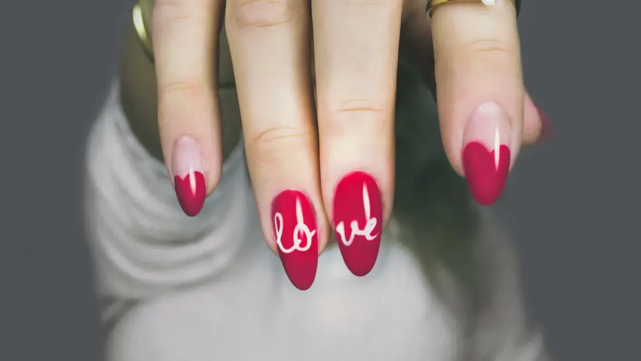 Dłoń z paznokciami w kształcie serca i napisem "love". Różne rodzaje paznokci, od klasycznych po te z ozdobami.