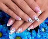 Dłonie z idealnym manicure, gdzie paznokcie na których nie widać odrostu zdobią klasyczny french i wzór panterki.