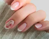 Delikatne paznokcie ślubne boho z subtelnym zdobieniem w postaci różowych kwiatów na jednym z paznokci. Klasyczny french manicure w nowoczesnym wydaniu.