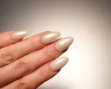 Dłoń z paznokciami w kształcie migdała, pomalowanymi na perłowy beż. Idealna krzywa C podkreśla elegancję manicure.