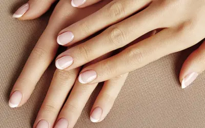 Dłonie z klasycznym french manicure. Delikatny róż i biel tworzą subtelny french pomarańczowy, podkreślając elegancję.