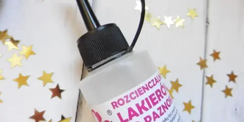 Butelka rozcieńczalnika do lakieru do paznokci, otoczona złotymi gwiazdkami.