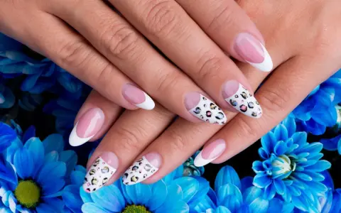 Dłonie z idealnym manicure, gdzie paznokcie na których nie widać odrostu zdobią klasyczny french i wzór panterki.