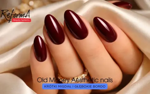 Eleganckie paznokcie w odcieniu głębokiego bordo, o migdałowym kształcie, ozdobione złotym pierścionkiem.