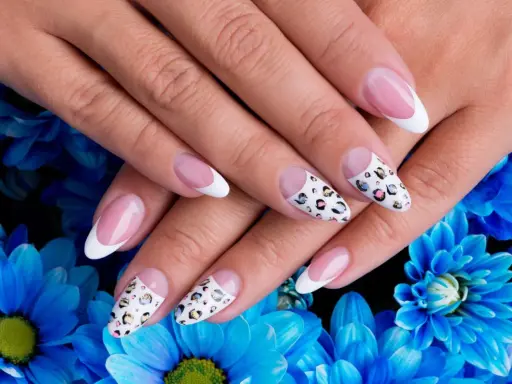Dłonie z idealnym manicure, gdzie paznokcie na których nie widać odrostu zdobią klasyczny french i wzór panterki.