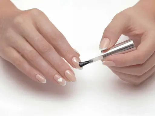 Dłonie z delikatnym manicure, gdzie paznokcie ślubne ze srebrem tworzą subtelny wzór serca.