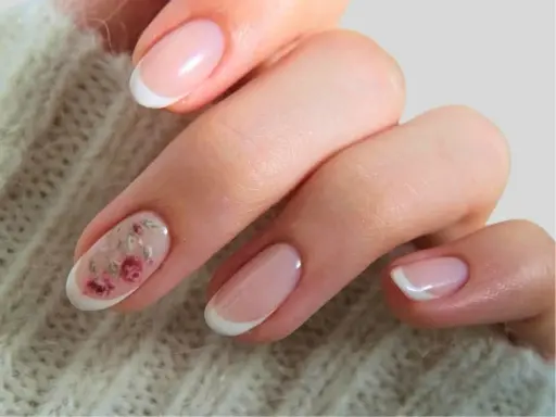 Delikatne paznokcie ślubne boho z subtelnym zdobieniem w postaci różowych kwiatów na jednym z paznokci. Klasyczny french manicure w nowoczesnym wydaniu.