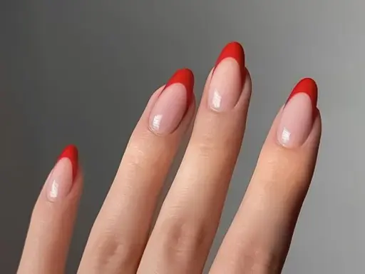 Dłonie z paznokciami w stylu czerwony french. Klasyczny manicure z wyrazistym, czerwonym akcentem na końcówkach.