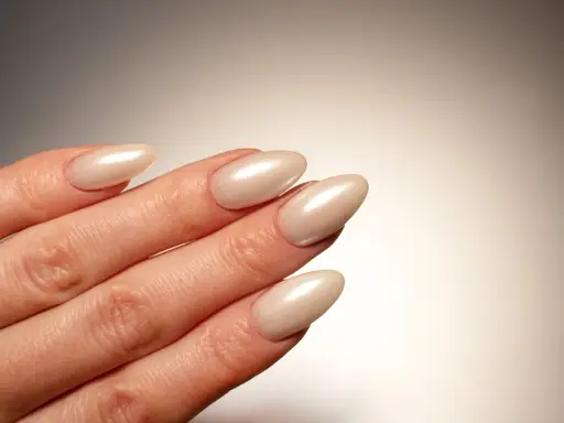 Dłoń z paznokciami w kształcie migdała, pomalowanymi na perłowy beż. Idealna krzywa C podkreśla elegancję manicure.