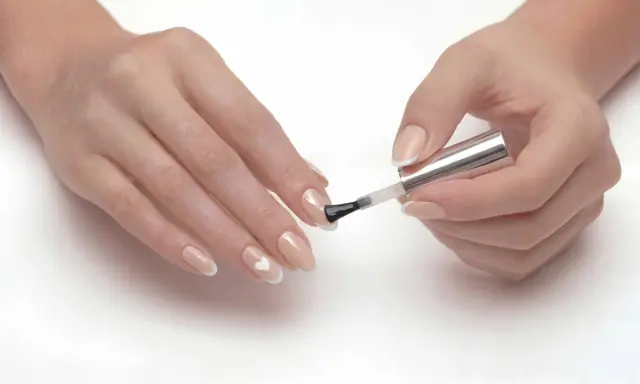 Dłonie z delikatnym manicure, gdzie paznokcie ślubne ze srebrem tworzą subtelny wzór serca.