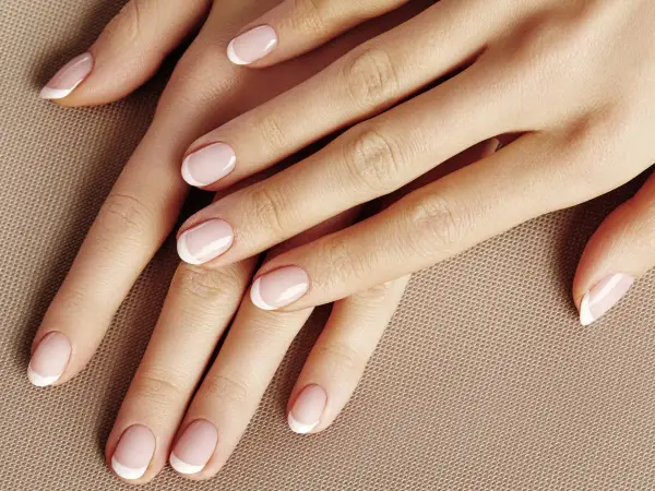 Dłonie z klasycznym french manicure. Delikatny róż i biel tworzą subtelny french pomarańczowy, podkreślając elegancję.